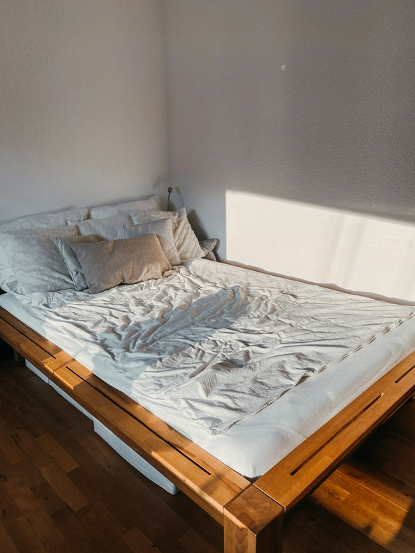 Opgemaakt bed in een rustige slaapkamer met ochtendlicht